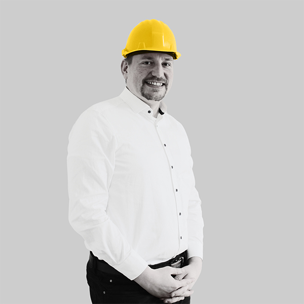 Team-rheform - Christoph Gaedke, M.Sc. Wirtschaftsingenieurswesen von der Zielorientierten Bedarfsplanung Standortkonzepte trägt einen Bauhelm und verschrenkt die Hände