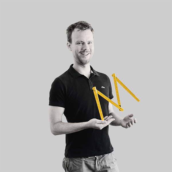 Team-rheform - Malte Wagner, M.Sc. Architekt von der Nachhaltigen immobilienentwicklung Gebäudeanalyse hält einen leicht aufgefaltenen Meterstab in einer Hand, der zu einem "M" geformt ist