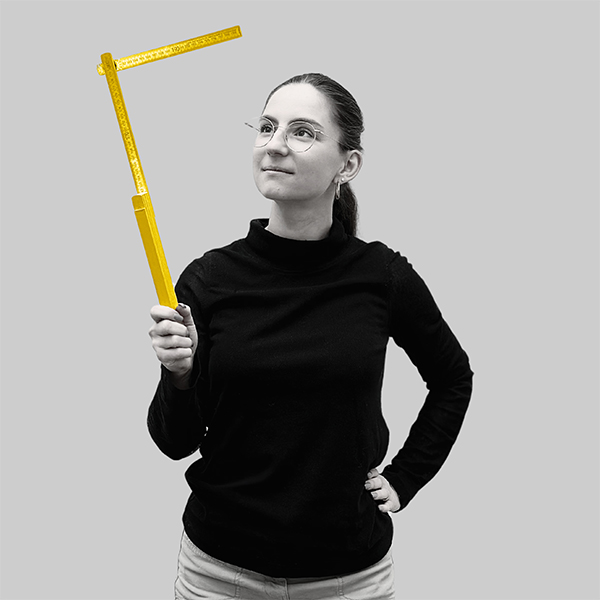 Team-rheform - Marlene Ehrmann, M.Sc. Bauingenieurswesen von der Nachhaltigen Immobilienentwicklung Gebäudeanalyse hält einen zu einem rechten Winkel gefaltenen Meterstab in der Hand, den sie anschaut